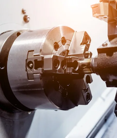 A lathe chuck holding a steel part as the cutting tool meets it