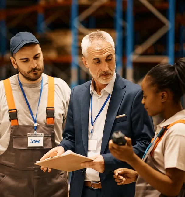 A manager and two warehouse staff checking an order on a clipboard
