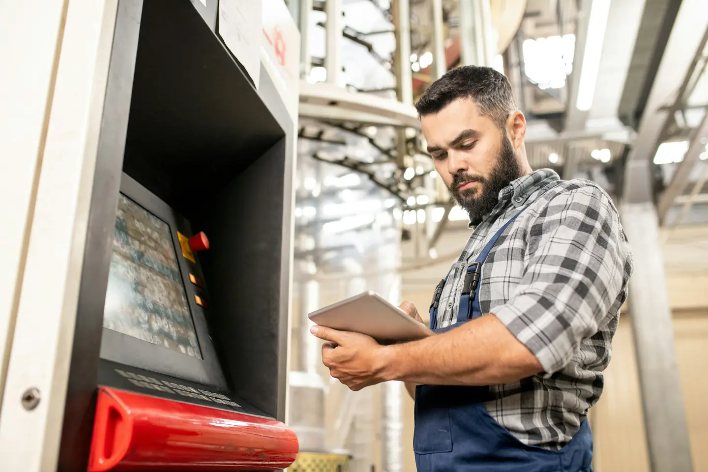 An engineer checking a tablet beside a machine on the factory floor